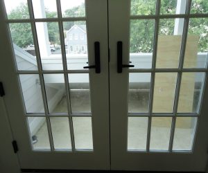 French doors open to a small concrete balcony with a wooden board leaning against the balcony railing.
