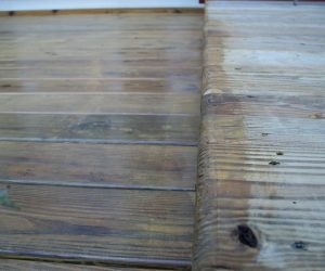Close-up of weathered wooden deck boards with a visible step leading to a slightly higher level.