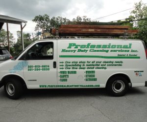 White van with “Professional Heavy Duty Cleaning Services” logo and contact info, ladders on roof, parked on street.